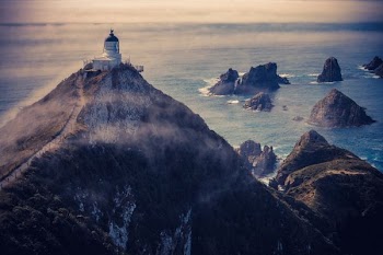 aerial view of a lighthouse atop of mountain