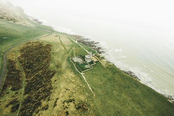Aerial View Of A Lighthouse By The Cliff Of A Plateau With Lush Vegetation