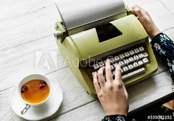 Aerial view of a woman typing on a retro typewriter blank paper