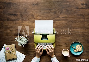 Aerial view of a woman typing on a retro typewriter blank paper