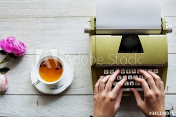 Aerial view of a woman typing on a retro typewriter blank paper