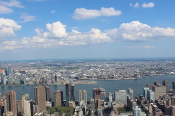 Aerial View of City Buildings by River Under Blue Cloudy Skies