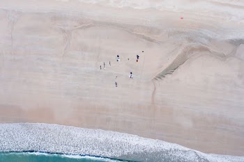 aerial view of group of people standing next to blue ocean water