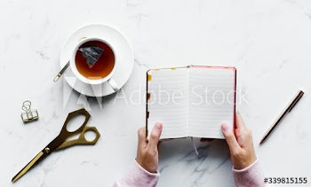 Aerial view of woman holding an empty journal and hot tea drink