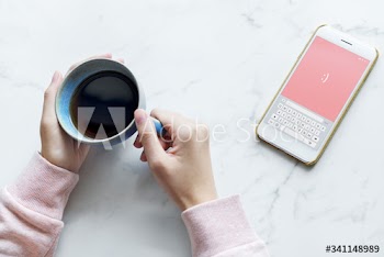 Aerial view of woman with a hot cup of coffee and a smartphone