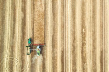 aerial view photography of tractor with disc harrow attachment on grass field
