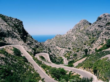 aerial view photography of zig-zag road surrounded of mountains and trees
