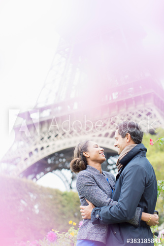 Affectionate couple hugging below Eiffel Tower, Paris, France
