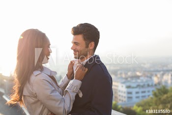 Affectionate couple hugging on sunny balcony, Paris, France