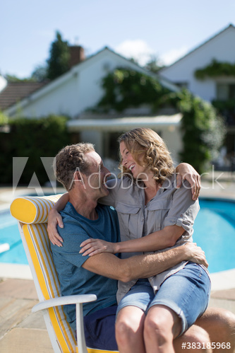 Affectionate couple hugging on sunny poolside