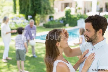Affectionate couple in backyard with family