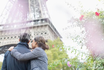 Affectionate couple standing below Eiffel Tower, Paris, France