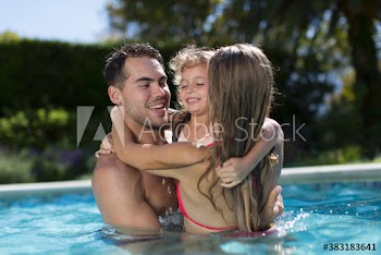 Affectionate family hugging in sunny swimming pool