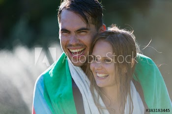 Affectionate happy young couple with wet hair sharing towel