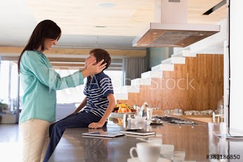 Affectionate mother and son talking at kitchen counter