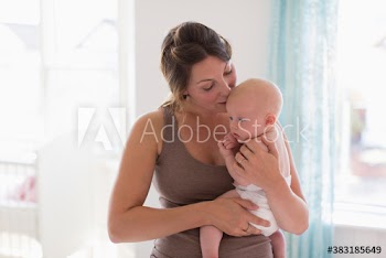 Affectionate mother holding and kissing baby son