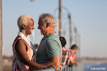 Affectionate senior couple face to face on sunny pier