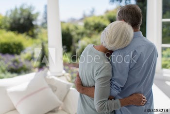 Affectionate senior couple hugging on sunny patio