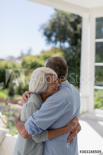 Affectionate senior couple hugging on sunny patio