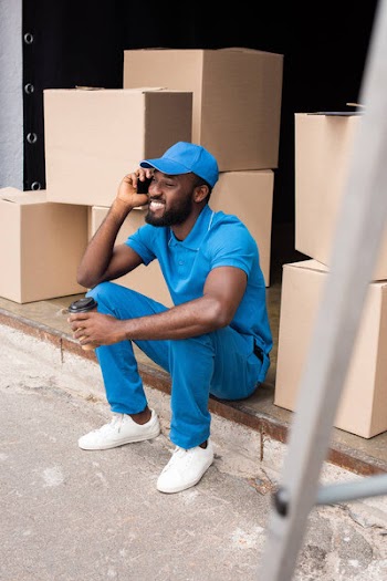 African american delivery man talking by smartphone and holding coffee in paper cup