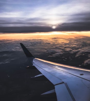 airplane on sky above white clouds during orange sunset