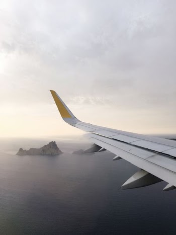 airplane wing above body of water during daytime