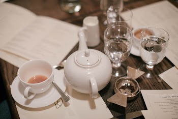Almost Empty Teacup by Teapot and Drinking Glass Cups at Table Top