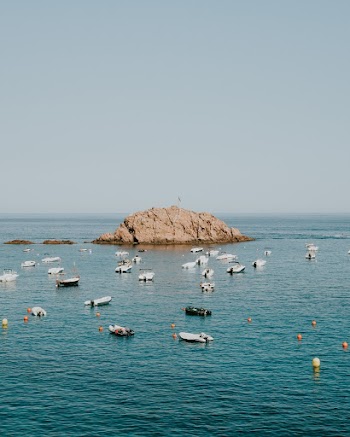 An Offshore Rock Formation Surrounded By Speedboats