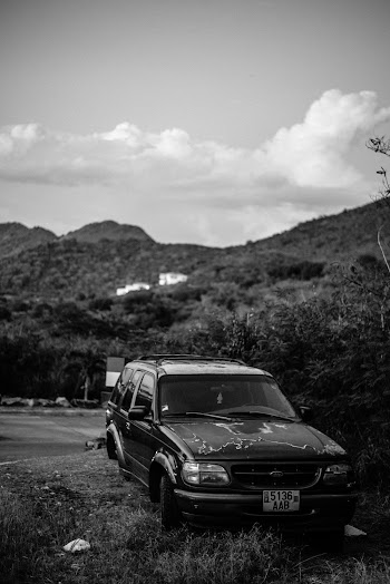 An Old Car Parked In A Grassland Near The Road