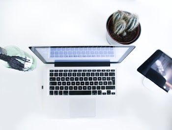 An up-top view of a laptop sitting on a white desk.