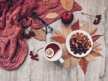Apple Beside White Ceramic Mug of Tea and Plate of Almonds and Nuts on Brown Wooden Table