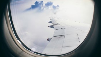 architectural photography of plane's wing above clouds during flight