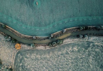 areal photography of river between grass fields