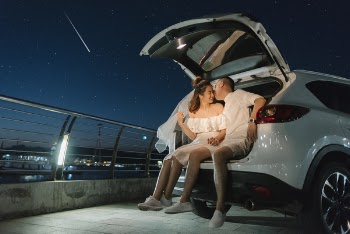 Asian couple sitting behind the car