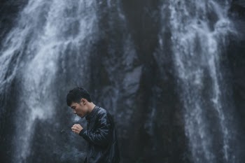 Asian man standing in front of the waterfall