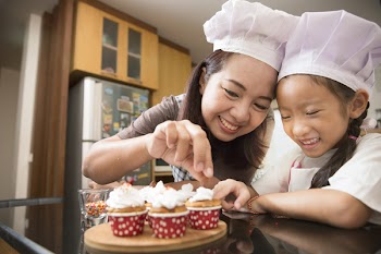 Asian mother and daughter enjoy making and decorate bakery cake in real life kitchen, Concept of family cooking
