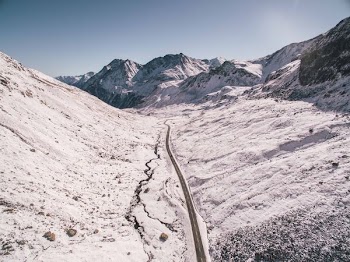 asphalt road between snow covered mountains under clear sky