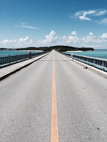 asphalt road near mountain under blue and white cloudy sky