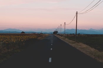 asphalt road near posts and mountains