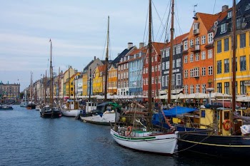 assorted-color boats beside assorted-color buildings at daytime