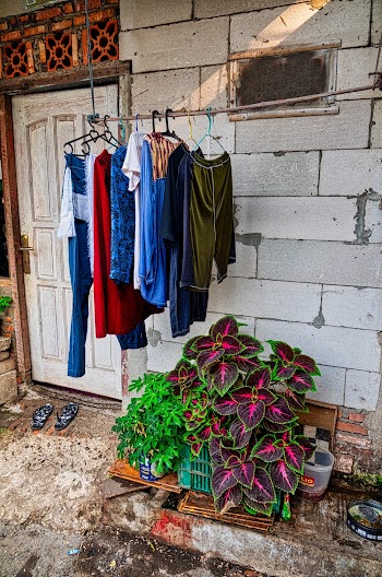 Assorted-color Clothes in Hanger on Rod Near Wall