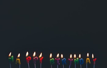 assorted-color Happy Birthday candles with flames