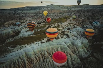 assorted-color hot air balloons flying above canyon