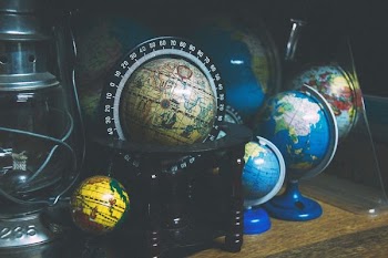 assorted mini desk globes on shelf near gray kerosene lantern