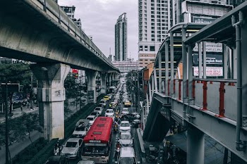 assorted vehicle on heavy traffic below train overpass during daytime