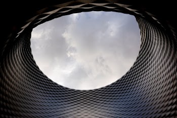 At the Messe Basel New Hall building there is a large gap in the building that allows people to see the sky from underneath the building overpass.