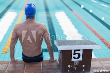 Athletic male swimmer sitting at edge of swimming pool