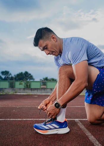 Athletic Man Tying Running Shoes at Track