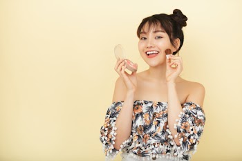 Attractive younf woman applying blush on her cheeks playfully Free Photo