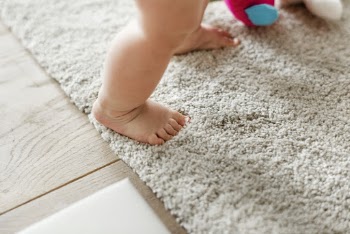 Baby's Standing on Gray Floor Rug
